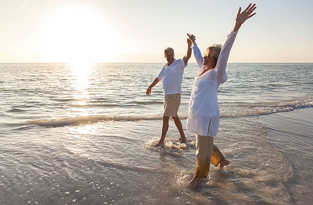istock Happy senior couple raising hands on beach 163727909