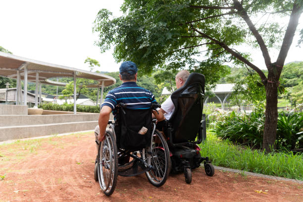 istock Two friends in wheelchairs taking a stroll in the park 1637279995