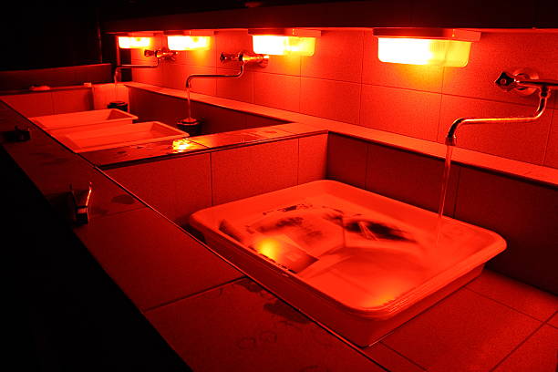 A close-up of sinks in a darkroom A photo of interior of darkroom in red light. darkroom photos stock pictures, royalty-free photos & images