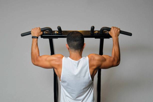 Strong Latin man doing pull-ups at a gym. stock photo