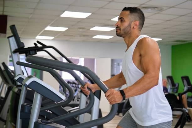 istock Strong Latin man doing elliptical training at a gym. 1637360215