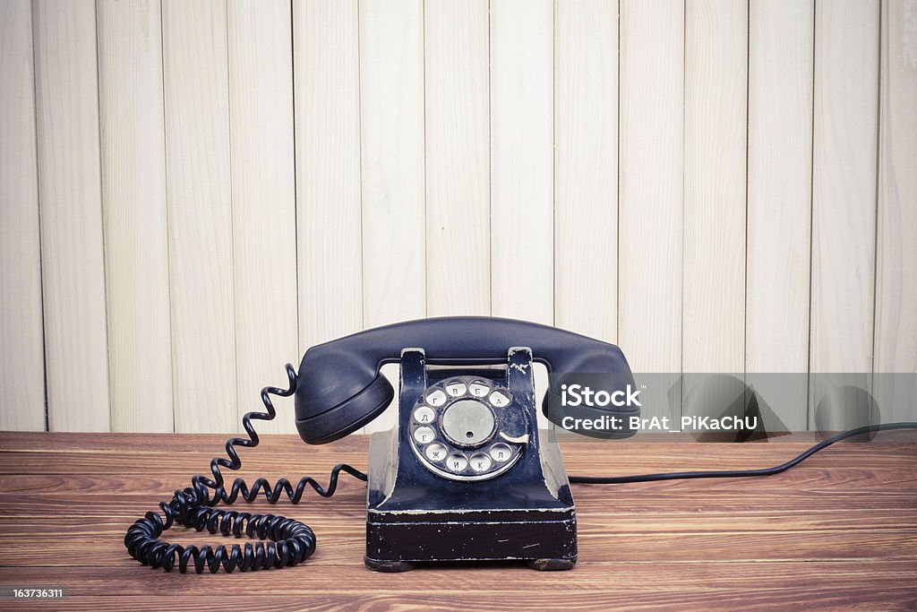 Vintage teléfono en la antigua mesa cerca de la pared de madera - Foto de stock de Anticuado libre de derechos