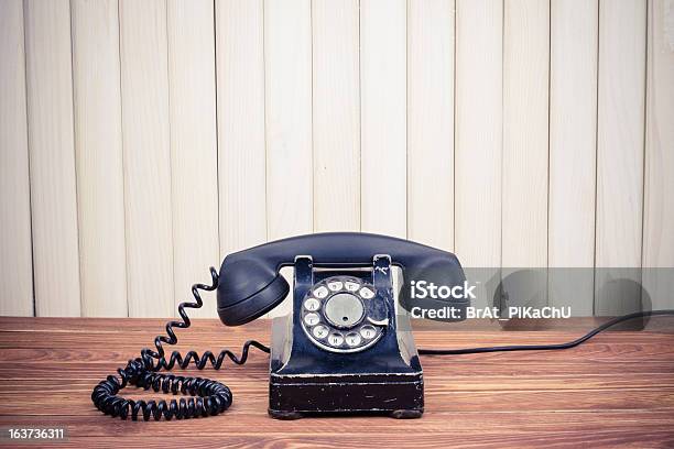 Foto de Telefone Antigo Em Uma Mesa De Madeira Velha Perto Da Parede e mais fotos de stock de Antigo