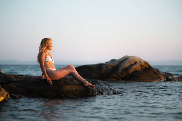 istock Beautiful woman sunbathing on a beach rock 1637376181