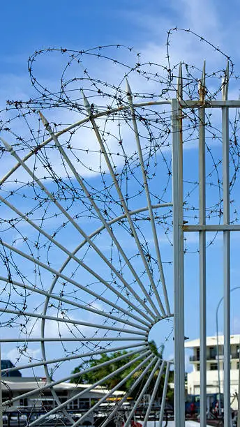 Barbed wire wrapped around a gate to increase the security of a private property; blue sky on the background