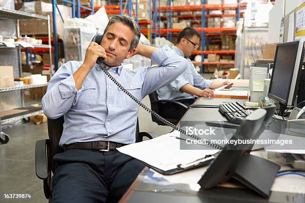 Businessman Taking Phone Call At His Warehouse Desk Stock Photo - Download Image Now