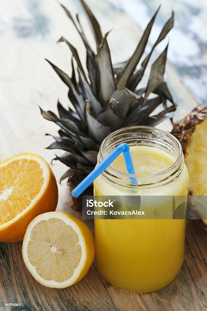 Health in fruits Fresh squeezed orange,lemon and pineapple juice arranged with full and cut fruits on wooden rustic table. Shallow DOF Antioxidant Stock Photo