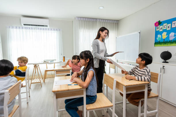 istock Group of student learn with teacher in classroom at elementary school. Attractive beautiful female instructor master explain and educate young children with happiness and fun activity at kindergarten. 1637427424