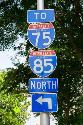 Interstate highway direction signs to I-96, I-295, and I-495 all on one pole on the side of a street next to a sidewalk