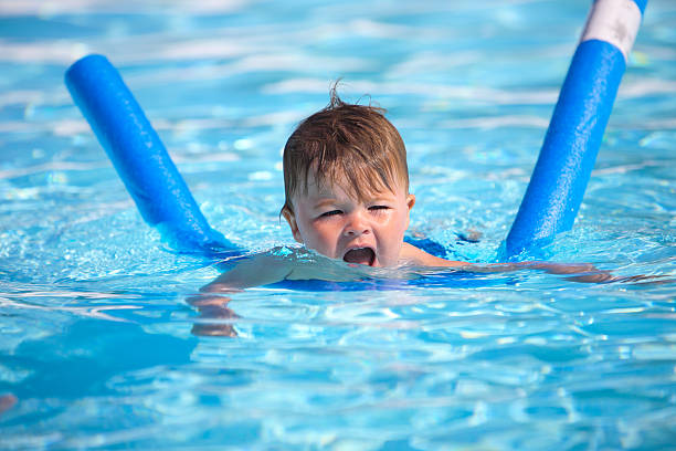 istock Happy little boy learning to swim with pool noodle 163743278