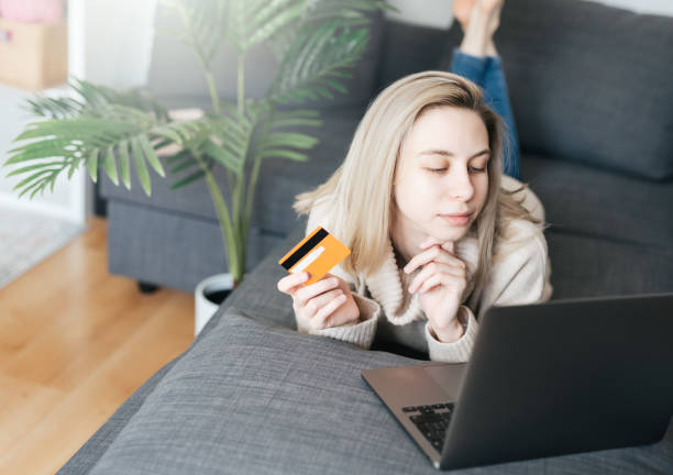 istock Young woman holding credit card and using laptop computer. 1637464042