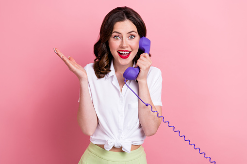 Photo of impressed funny woman dressed white shirt talking vintage landline phone isolated pink color background.