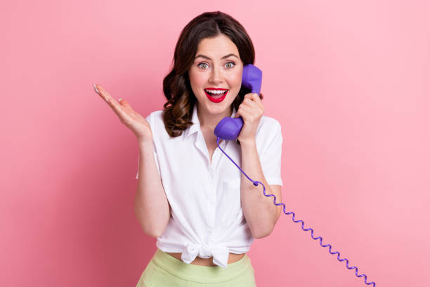 Photo of impressed funny woman dressed white shirt talking vintage landline phone isolated pink color background stock photo