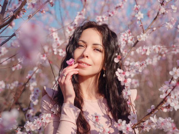 istock A beautiful young woman near a blooming spring pink tree 1637497222