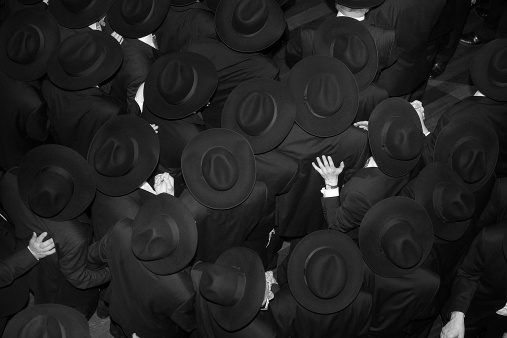 a crowded group of religious Jewish Men dancing at a wedding