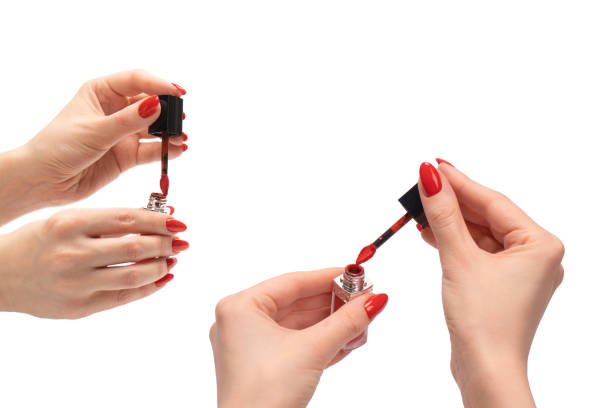 czerwona płynna szminka w dłoniach kobiety z czerwonymi paznokciami izolowana na białym tle. - red nail polish zdjęcia i obrazy z banku zdjęć