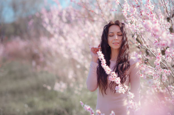 istock A beautiful young woman near a blooming spring pink tree 1637519527