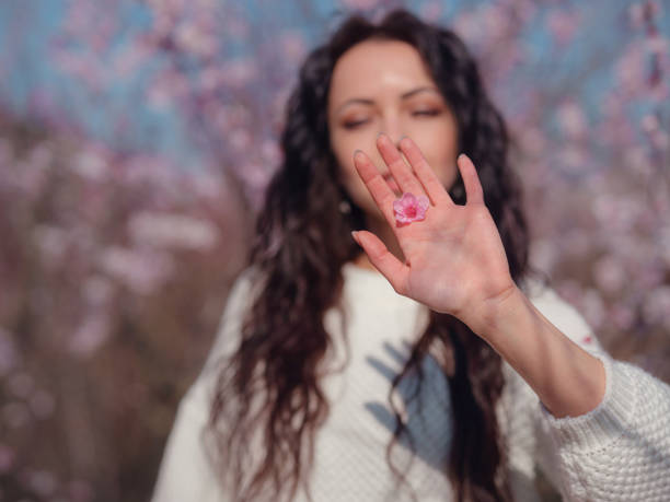 A beautiful young woman near a blooming spring cherry blossom tree. The idea and concept of renewal, self-care, health and happiness, Japan style