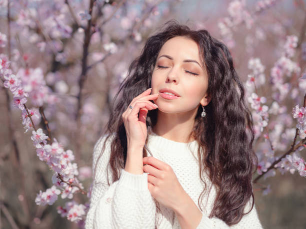 istock A beautiful young woman near a blooming spring pink tree 1637523316