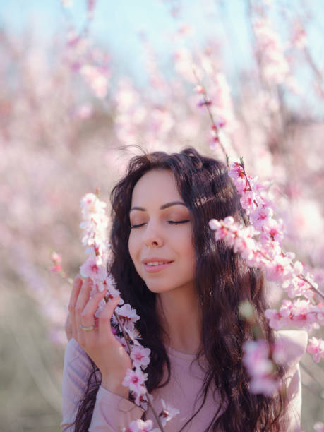 istock A beautiful young woman near a blooming spring pink tree 1637525906
