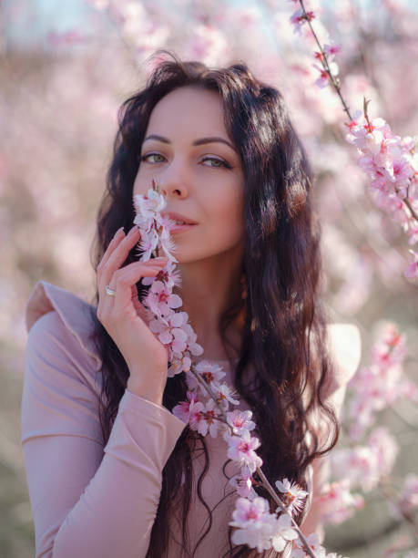 istock A beautiful young woman near a blooming spring pink tree 1637525936