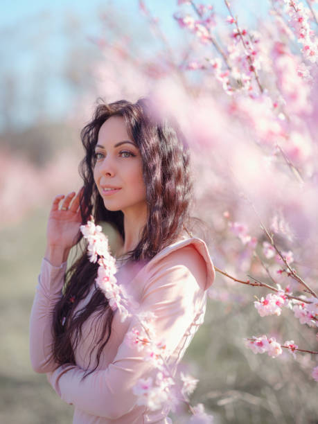 istock A beautiful young woman near a blooming spring pink tree 1637531961