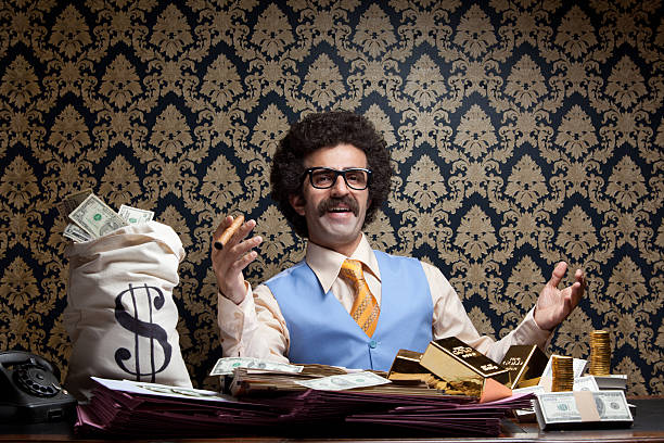 Rich man posing with money bags, gold bullions, dollar bills Horizontal photo of rich man posing with money bags, gold ingots and dollar bills and sitting on table.He has long hair and mustache and wearing a blue waist and a yellow necktie.Wallpaper is on the background.Model is holding cigar in right hand.Vignette light effect achieved during shot.Full frame DSLR camera was used. rich man stock pictures, royalty-free photos & images
