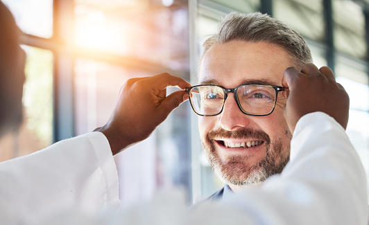 Optometry, doctor and glasses for a happy man at a clinic for vision, healthcare and help with eyes. Smile, retail and a male customer with an optometrist and eyewear during a medical consultation