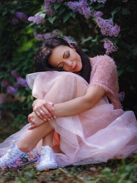 istock a young woman walking in a spring lilac garden 1637550450