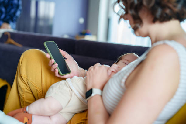 istock Mother breastfeeding her baby and using mobile phone at home. 1637552609