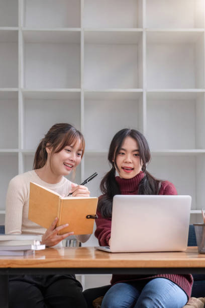 istock Two young female students tutoring and catching up workbook together 1637553158