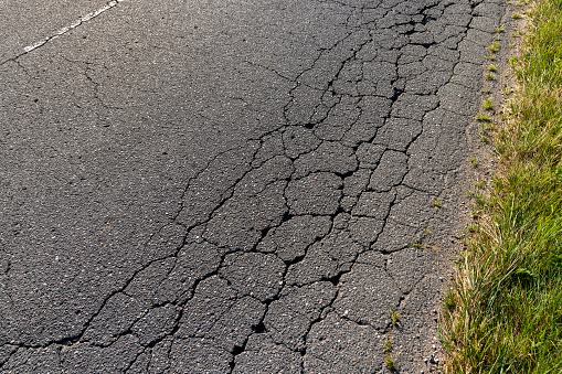 A damaged road dangerous for traffic, pits and cracks on the asphalt of the road