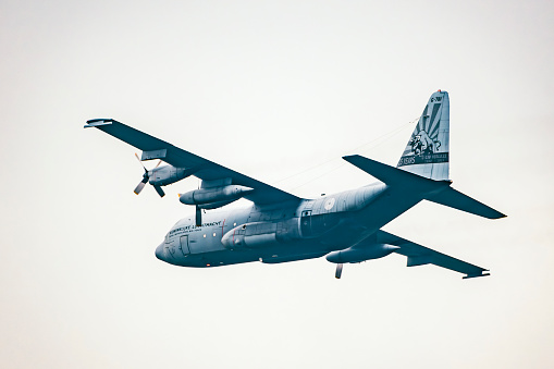 Lockheed C-130 Hercules of the Royal Netherlands Air Force (RNLAF) flying in mid air during sunset near Deelen airflield at the Veluwezoom nature reserve in Gelderland, The Netherlands.