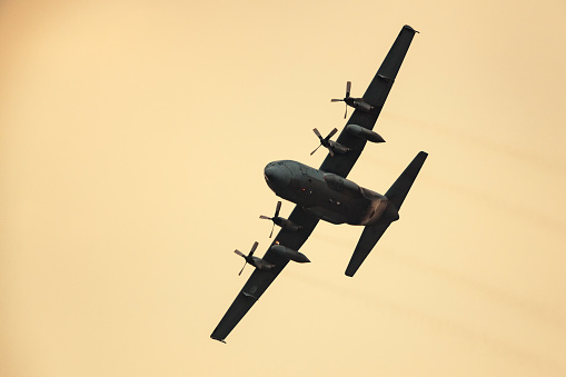 Lockheed C-130 Hercules of the Royal Netherlands Air Force (RNLAF) flying in mid air during sunset near Deelen airflield at the Veluwezoom nature reserve in Gelderland, The Netherlands.