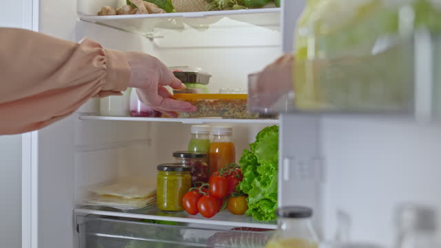 LD Female hand placing a packed lunch into the fridge