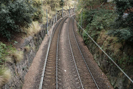 Section of double train tracks going round a bend with greenery either side.