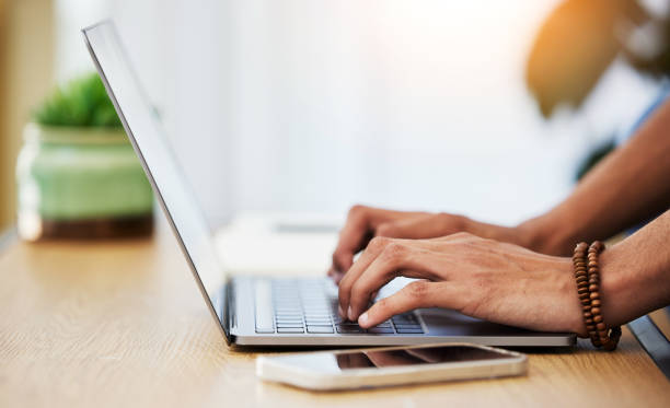 istock Closeup, work from home and hands with a laptop, typing and connection with network, smartphone and keyboard. Person, entrepreneur or freelancer with pc, deadline and search internet for website info 1637599324