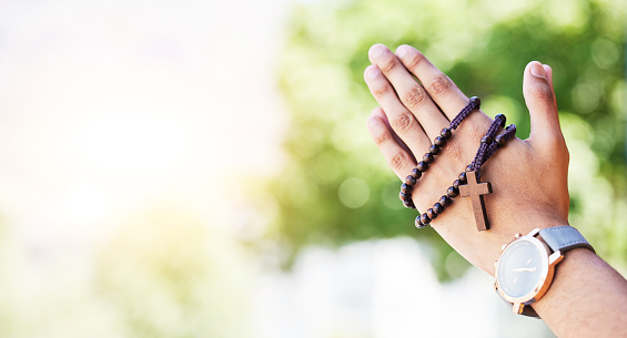 Faith, hands praying and rosary in garden with mockup, praise and religion with holy mindset. Christian prayer beads, cross and person in worship in nature with hope, spiritual gratitude and space.