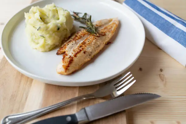 Healthy homemade meal  with natural pan fried pangasius fillet. Served with fresh cooked mashed potatoes and zucchini. Served ready to eat on a plate. Light food