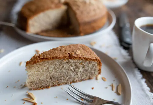 Gluten free cake with almond flour. Served sliced on a plate with fork on wooden table. Closeup