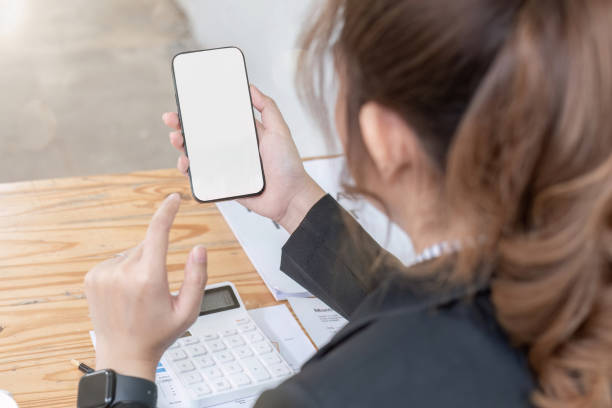 istock Woman holding phone showing white screen on top view while sitting in office 1637626971