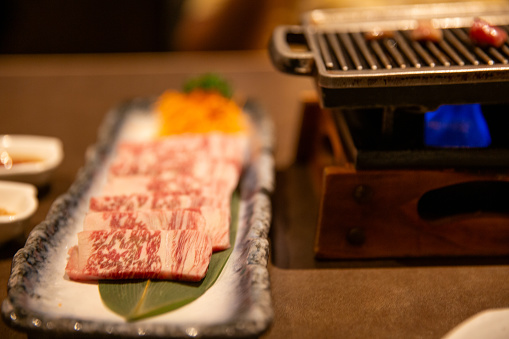 Raw wagyu beef next to a grill