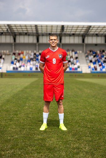 Portrait of smiling male football player standing on football pitch during match.