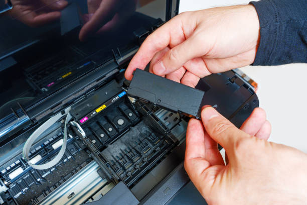 istock Holding Unpacked Inkjet Printer Cartridge in Hands over the Carriage 1637676665
