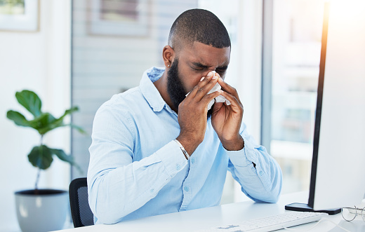 Allergy, blowing nose or sick businessman in office or worker with hay fever sneezing or illness in workplace. Sneeze, black man or trader with toilet paper tissue, virus or flu disease at desk