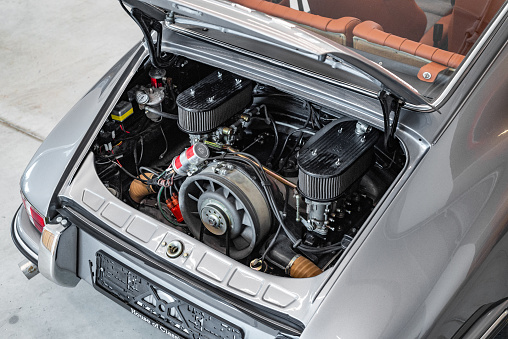 Vilnius, Lithuania - April 11, 2023: 1969 Porsche 911T, surrounded by other vintage cars in a private collection. Car after full restoration, painted in elegant grey colour. View to engine bay.
