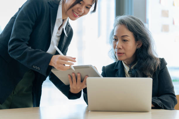 istock Two diverse financial assistant working together while senior professional sitting and discuss investment 1637685293