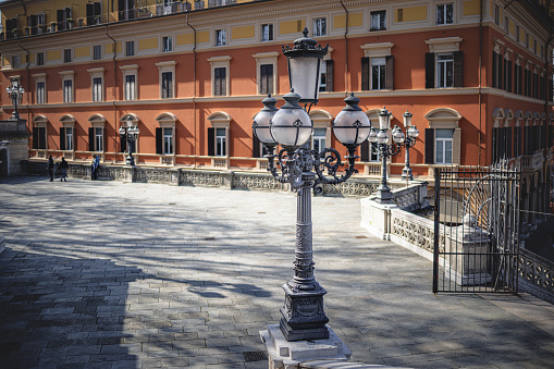 Stone paved patio with street light and residential building in Montagnola Park complex, Bologna, Italy