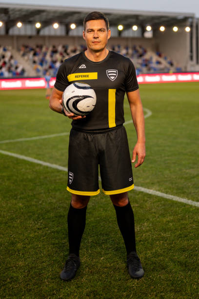 istock Portrait of referee standing with ball on pitch 1637717323