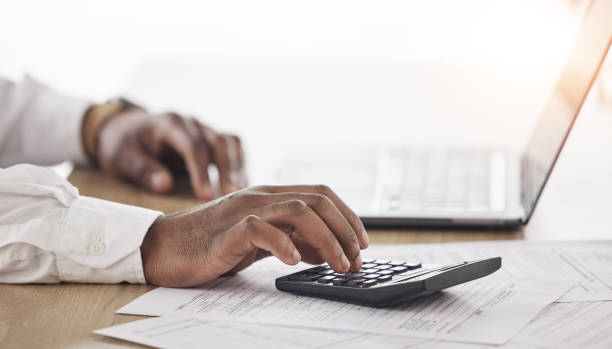 istock Person, hands and calculator, computer and documents for financial planning, taxes management and business debt. Accountant typing numbers for budget, bookkeeping math and audit paperwork on laptop 1637725152